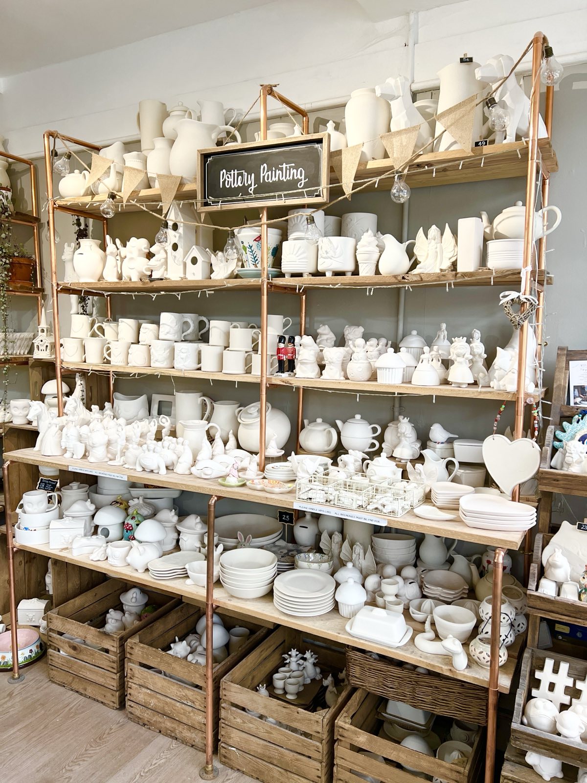 Display of ceramic items on wooden shelves at wick & ceramic pottery cafe
