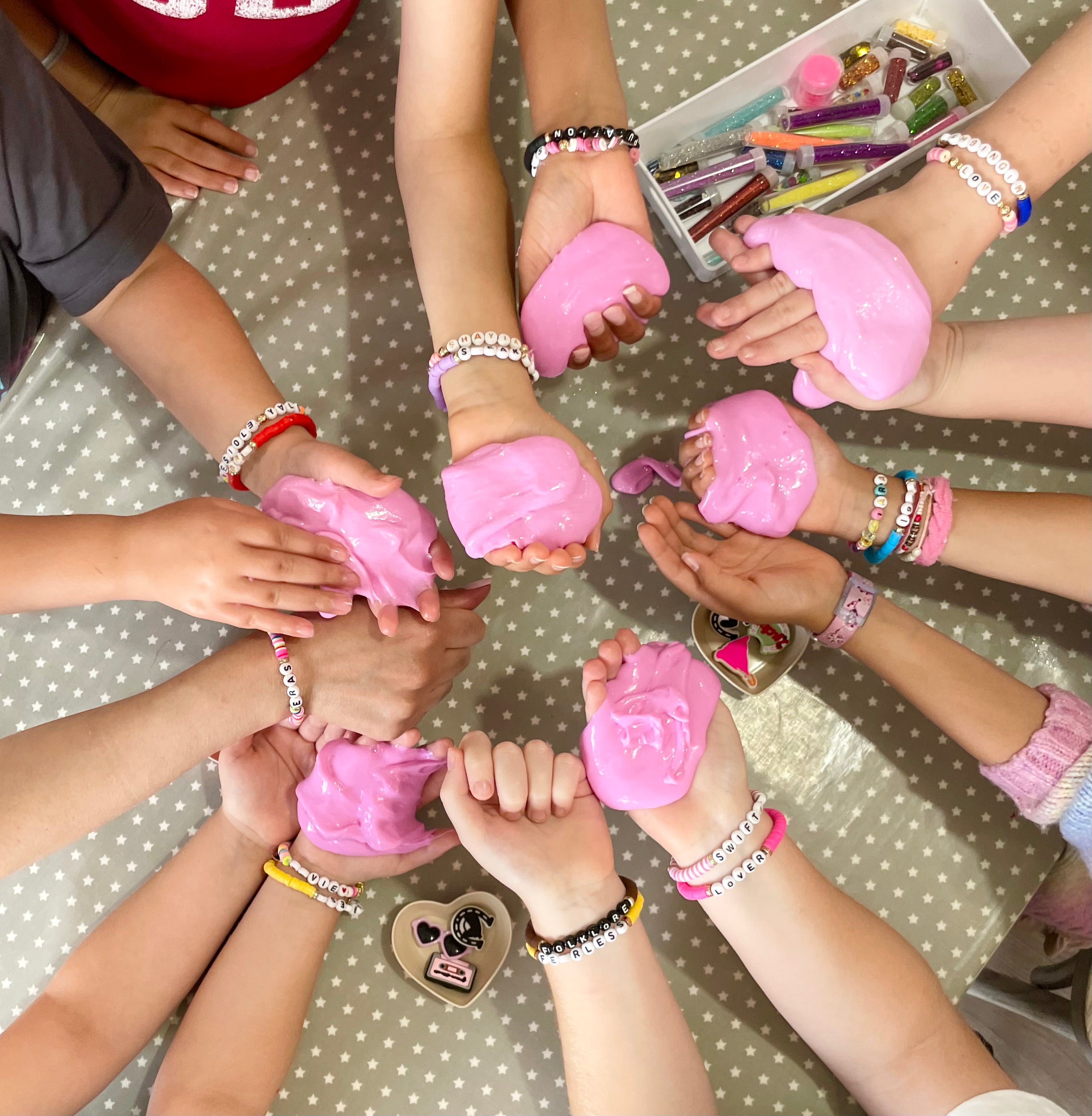Children's hands holding pink slime on a polka dot surface slime party