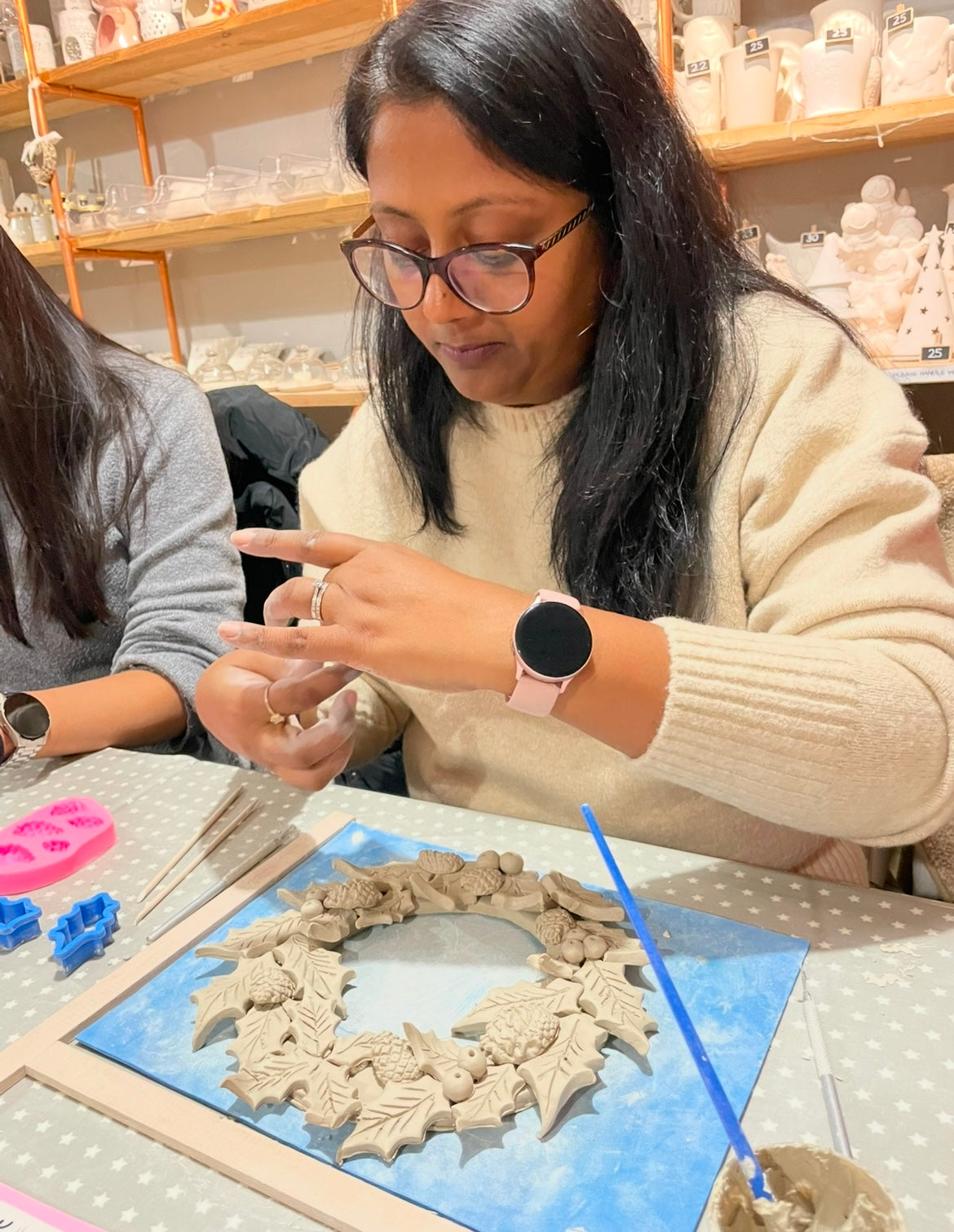 Woman working on a ceramic christmas wreath at wick & ceramic pottery studio ickenham london