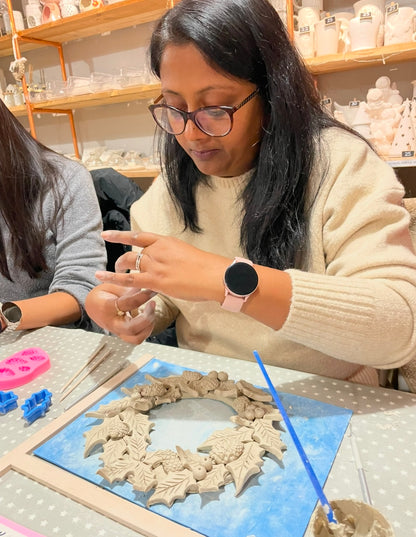 Woman working on a ceramic christmas wreath at wick & ceramic pottery studio ickenham london