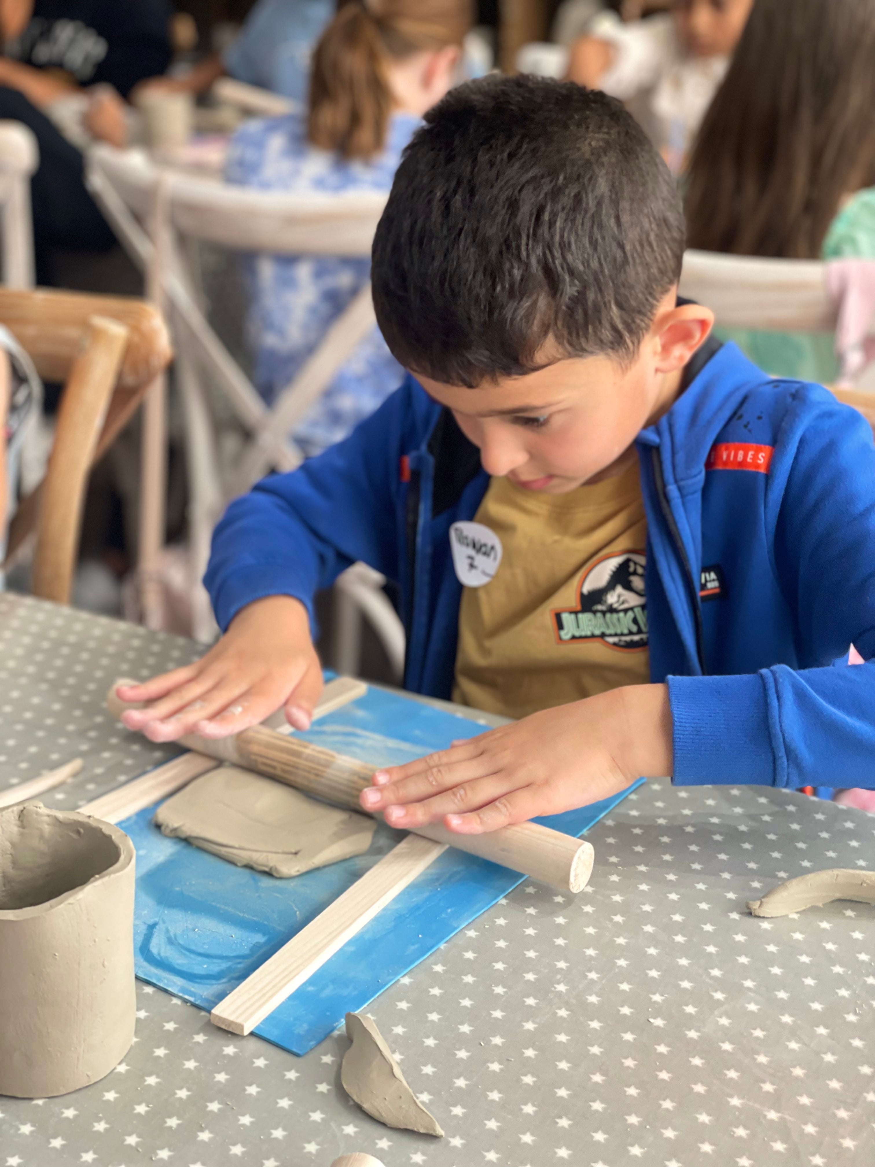 boy using a roller pin to flatten clay mug making wick & ceramic ickenham london