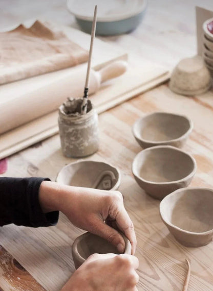 Person working on pottery with clay bowls on a wooden table wick & ceramic ickenham london