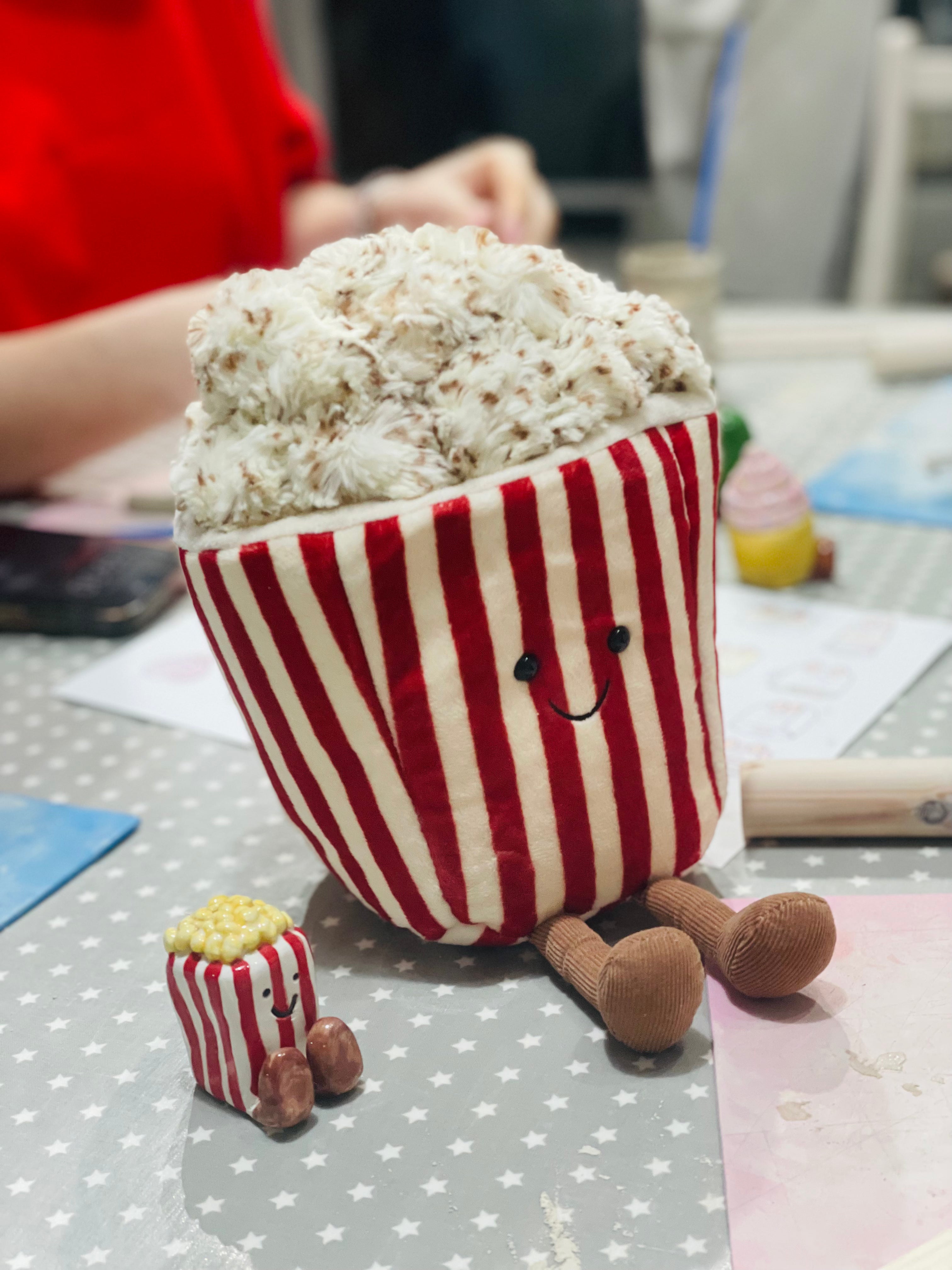 Jellycat Plush toy resembling a popcorn container next to a popcorn mini jellycat clay figure
