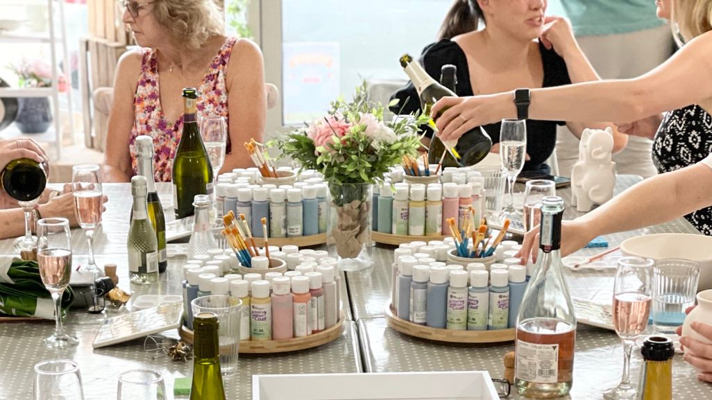 Group of women at a table with prosecco bottles whilst pottery painting ceramics wick & ceramic ickenham london