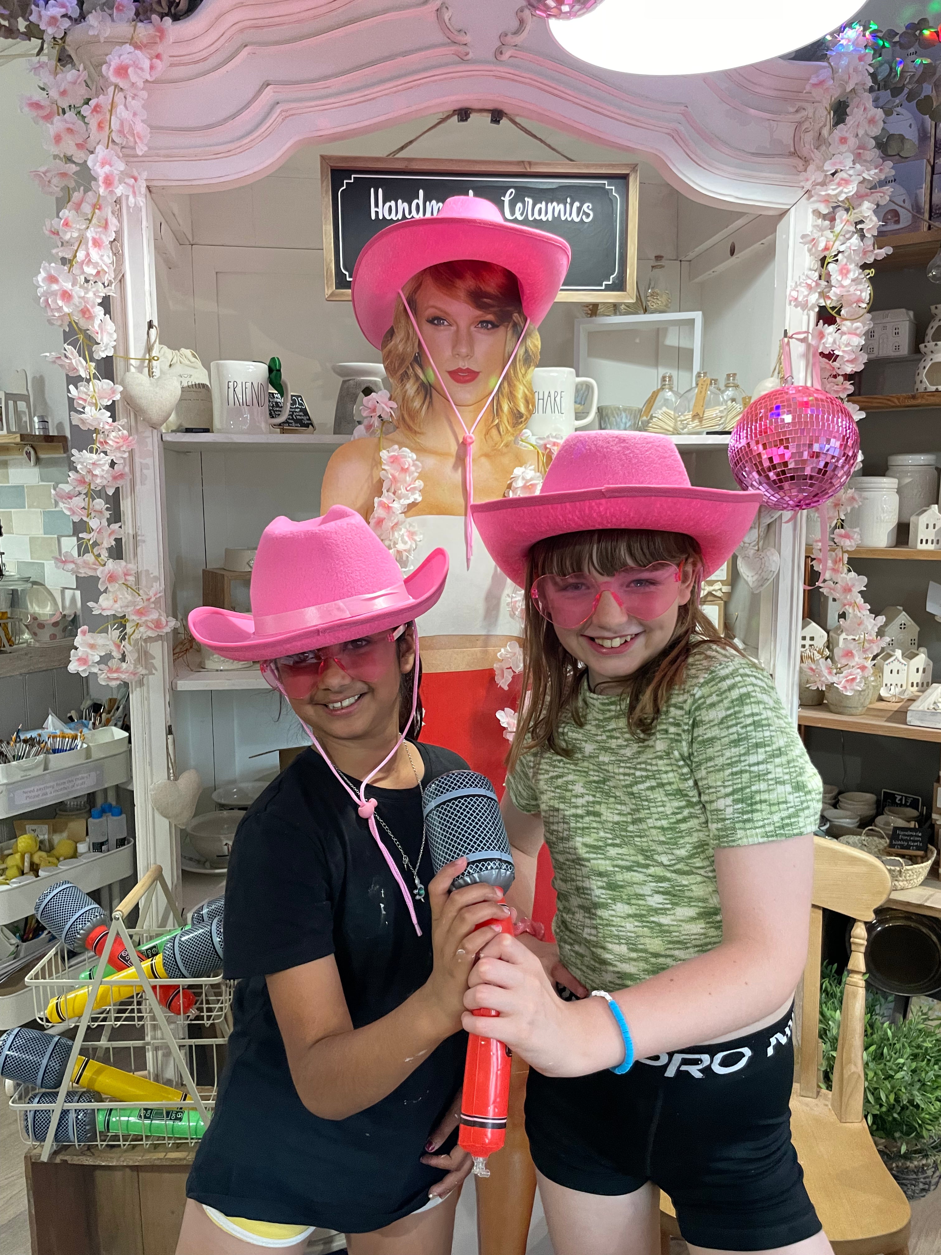 Two children wearing pink cowboy hats and sunglasses alongside a taylor swift model at wick & ceramic ickenham london