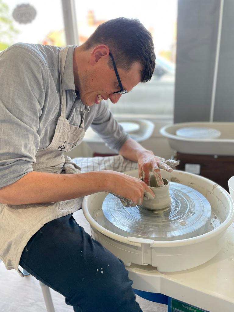 Man smiling while enjoying a Wick & Ceramic pottery wheel throwing experience in Ickenham, London.