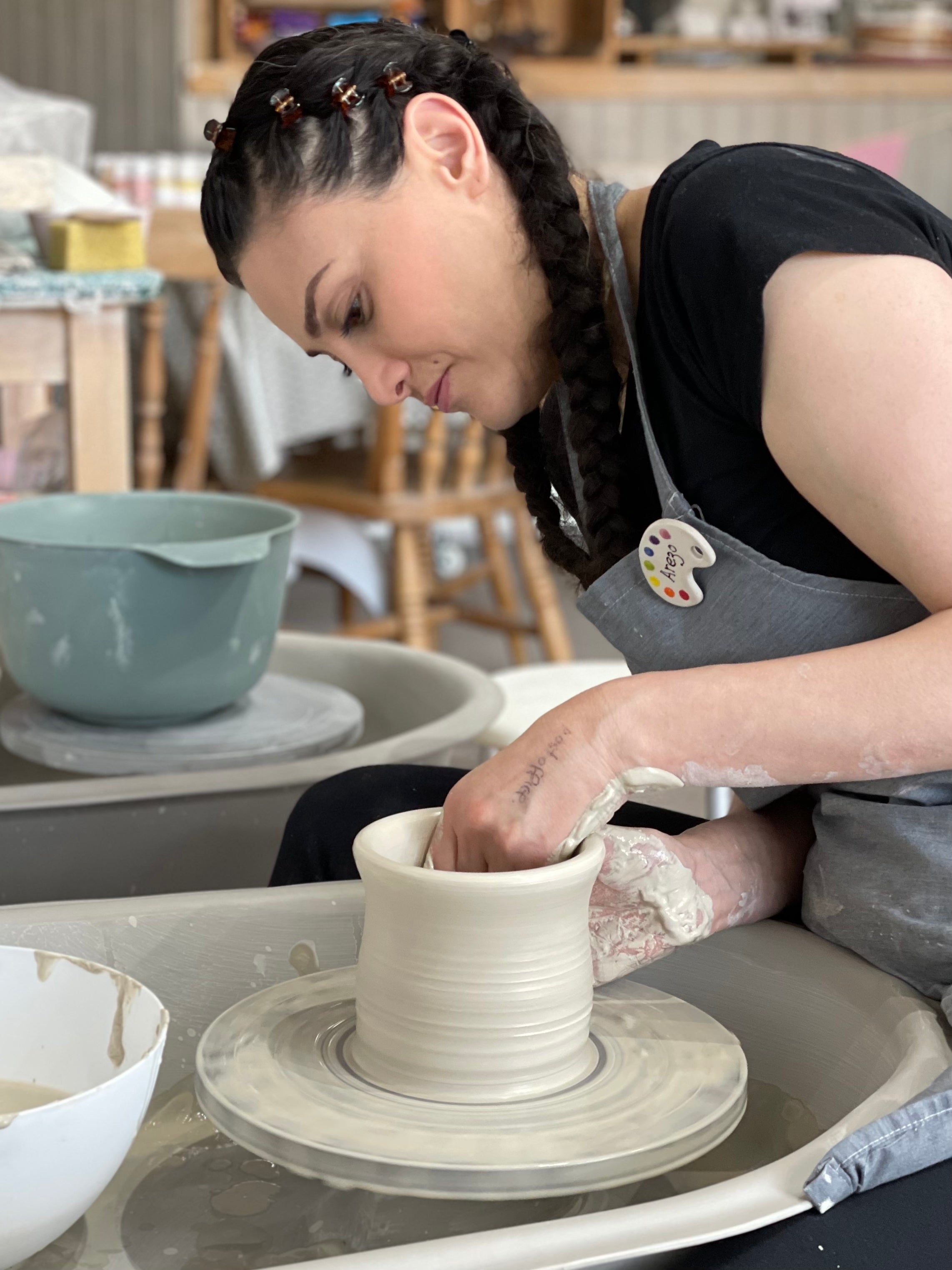 Lady making a clay pot on the wheel at Wick & Ceramic in Ickenham, London.