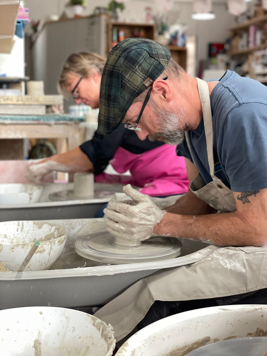 Man concentrating on shaping clay during a Wick & Ceramic wheel throwing pottery making experience in Ickenham, London.