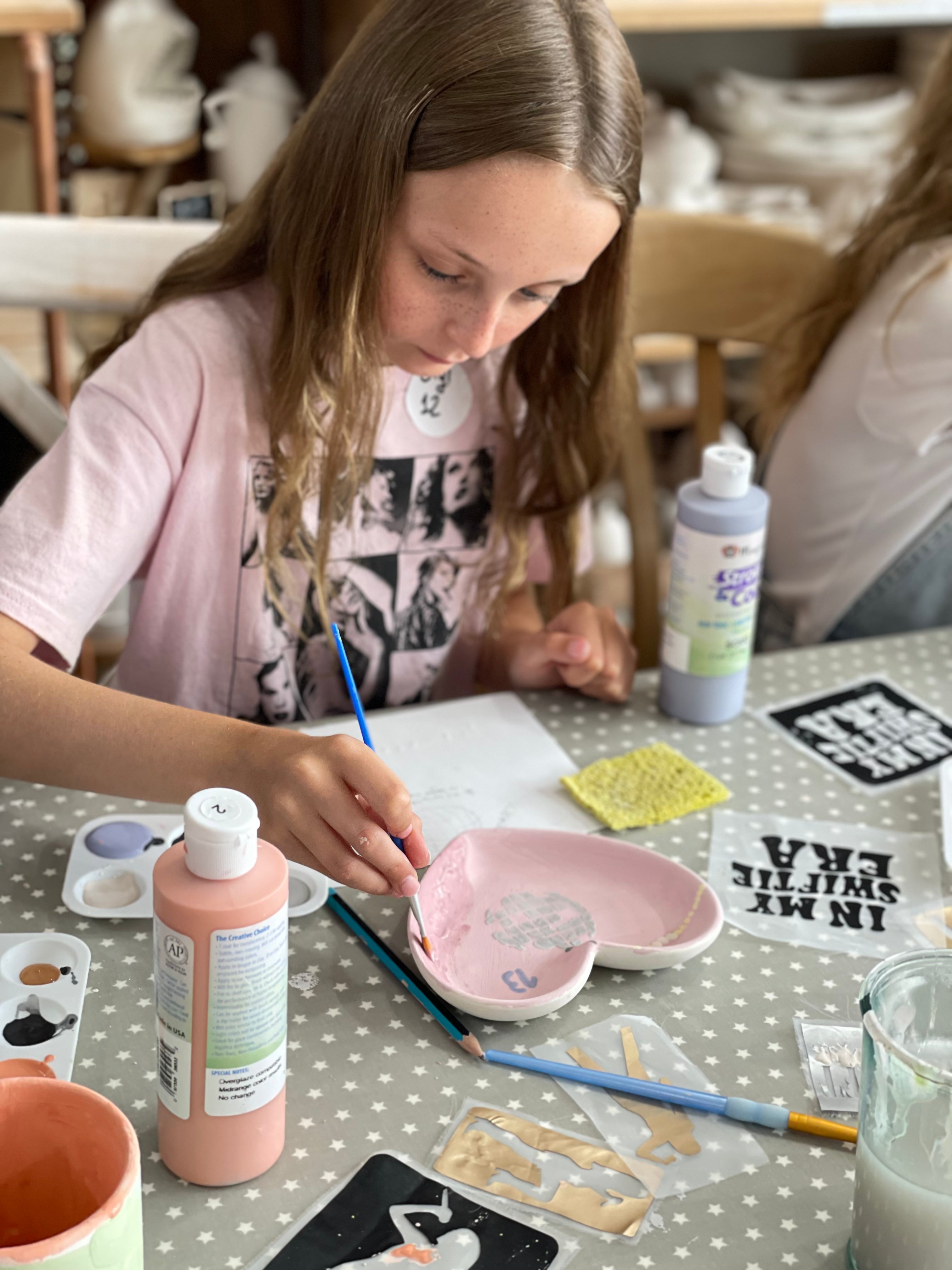 young girl paining a taylor swift themed, heart shaped plate at wick & ceramic ickenham london